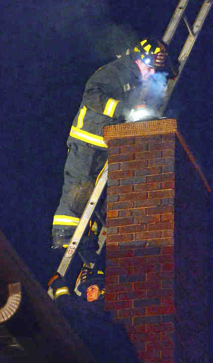 About a dozen Leetonia firefighters and EMS personnel responded to a chimney fire at the Ben Cope residence. The fire was contained within the chimney flue and there were no injuries to the family of five or the firefighters. Leetonia firefighter Dan Joy drops a device down the chimney flue to clear any blockage as firefighter Dallas Wright steadies the ladder on the roof of the home.    (Patrica Schaeffer / The (Lisbon) Morning Journal)